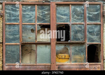 Broken glass panes covered in thick spider webs Stock Photo