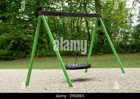 Green outdoor swing set with nest basket swing in public park on playground. Stock Photo
