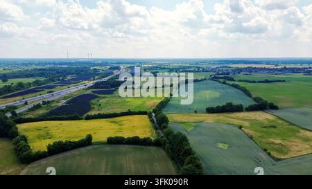 Rural landscape showing green fields, solar panels, moving traffic on a highway, and wind turbines Stock Photo