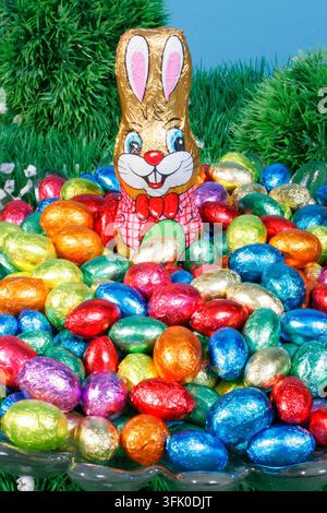 A chocolate Easter bunny sits on many colorful Easter eggs made of chocolate, chocolate eggs, eggs, sweets Stock Photo