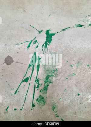 Green splashes and drips of paint creating abstract pattern on a textured grey concrete surface Stock Photo