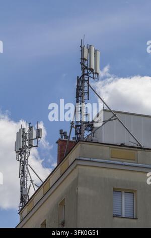 Telecommunication antennas and equipment mounted on a rooftop structure against a cloudy blue sky. Stock Photo