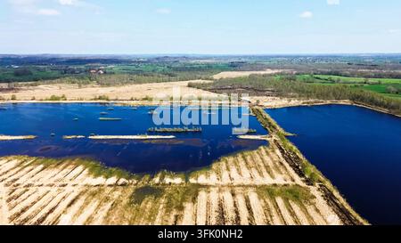 Aerial view showing peat bog landscape with water pools and drained areas under a blue sky Stock Photo