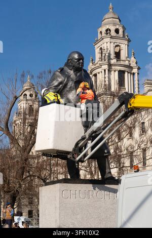 Workers clean the Winston Churchill statue in Parliament Square, London, using a lift for routine maintenance. Stock Photo