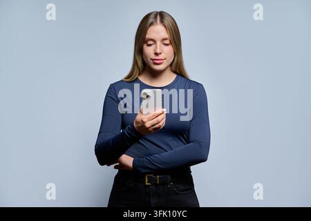 Young woman in dark blue top looking at smartphone Stock Photo