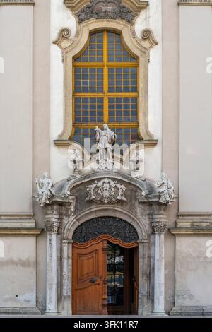 The baroque side entrance of St Anne's Parish Church shows a wooden double door beneath a carved stone pediment and a large arched window framed by sc Stock Photo