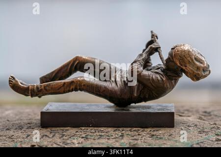 The Flutist, a small bronze miniature sculpture by artist Mihaly Kolodko, depicts a barefoot boy in a cap lying on his back and playing a flute, mount Stock Photo