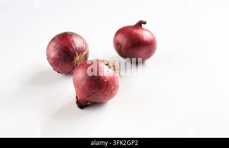 Red onions three ripe purple bulbs isolated on white background. Vegetable,  produce, healthy nutrition, and organic food ingredients. Stock Photo