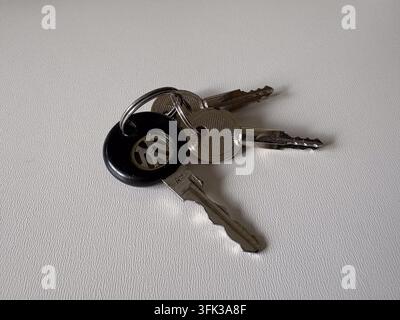 Vintage 1990s Volkswagen Jetta car keys with logo fob resting on a neutral white textured background. Stock Photo