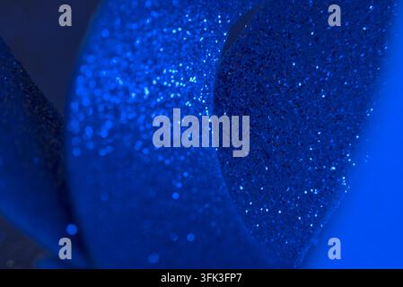 Curled blue glitter ribbon showing sparkling details close-up. Stock Photo