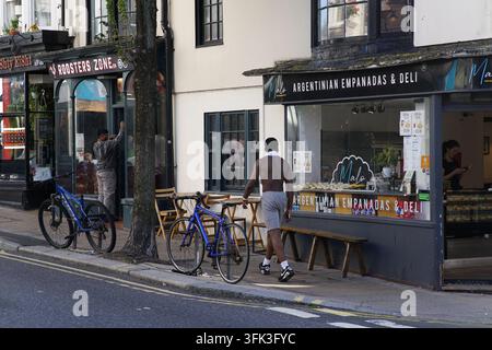 Bicycles parked outside an Argentinian empanadas deli and neighbouring shops on a Brighton street, England. Stock Photo