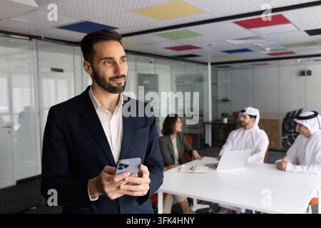 Pensive Hispanic businessman checking smartphone in office Stock Photo