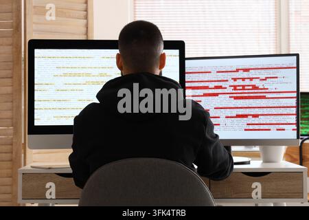 Software development and debugging, programmer working on computer code with error logs and syntax issues on dual monitors in a home office workspace Stock Photo