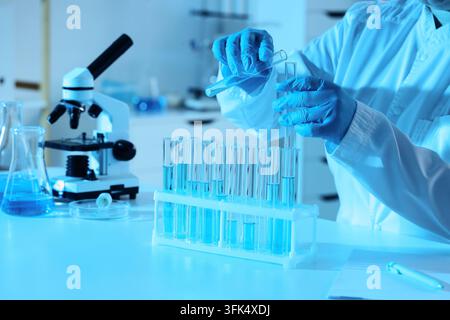 Medical research and pharmaceutical development, scientist pouring blue liquid into test tube for clinical trial analysis in a modern laboratory Stock Photo