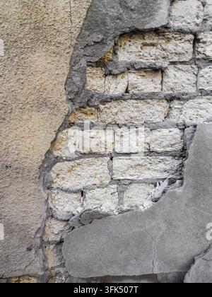 The plastered wall is beige in places. White brickwork is visible through the crumbling plaster. The contours resemble an elephant's head with a trunk Stock Photo