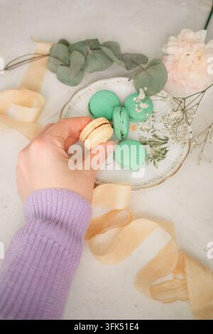 Female hands holding macaroon cookies with dried flowers and ribbons Stock Photo