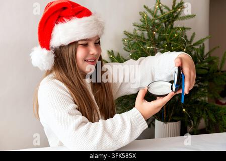 Happy teen girl receives clear orthodontic aligners as Christmas gift, festive concept for teeth straightening, modern dentistry and New Year smile Stock Photo