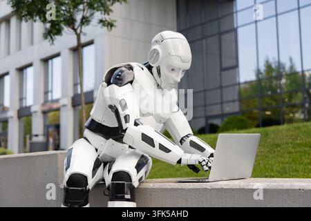 White cyborg typing on modern notebook outside contemporary business center Stock Photo