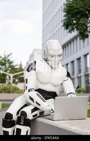 Smart android typing on laptop computer in modern urban business district Stock Photo