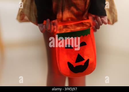 Cropped view of child holding orange felt pumpkin bag for Halloween Stock Photo