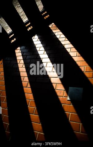 Diagonal shadow stripes from window panes on red brick wall Stock Photo
