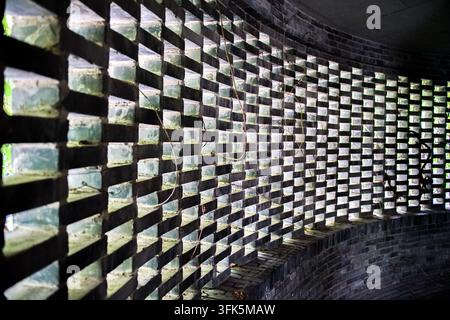 Geometric shadows on curved hollow blue brick wall in a garden Stock Photo