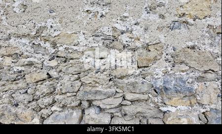 Very old weathered house wall with exposed stones beneath the plaster, Switzerland Stock Photo