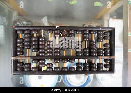 Close-up of an old rosewood abacus lying flat on a glass cabinet surface Stock Photo
