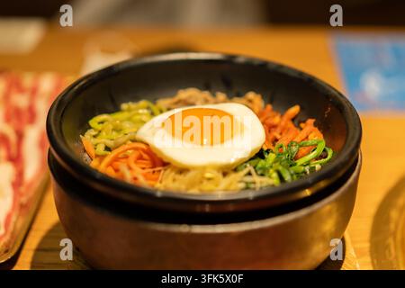 Close-up of Korean bibimbap with fried egg in hot stone pot Stock Photo