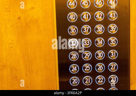 Close-up view of a modern stainless steel elevator control panel with glowing blue numbered buttons. Stock Photo