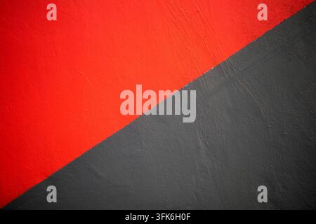 Minimalist abstract background featuring painted concrete wall divided diagonally into bright red and dark grey areas with copy space. Stock Photo