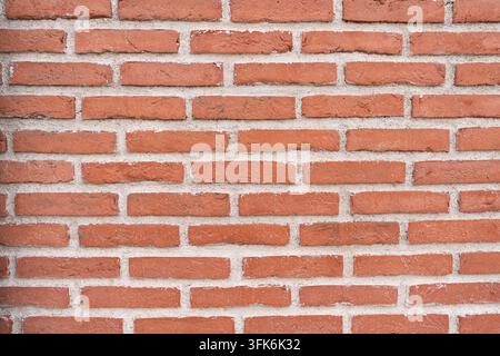 Regular red brick wall with clean geometric lines, uniform masonry and light mortar joints, creating a structured architectural background with strong Stock Photo