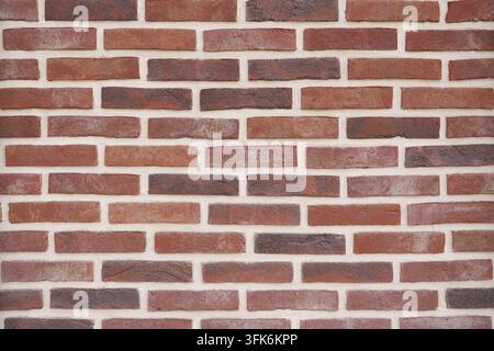 Traditional red brick wall photographed closely to emphasize repeating horizontal lines, contrasting bricks and mortar joints, creating an architectur Stock Photo