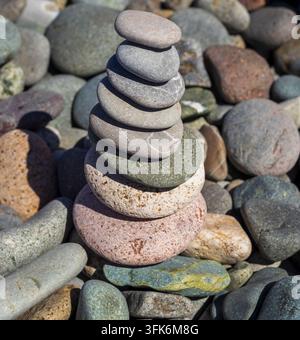 A tall vertical tower of balanced smooth sea stones on a pebble beach. Stock Photo