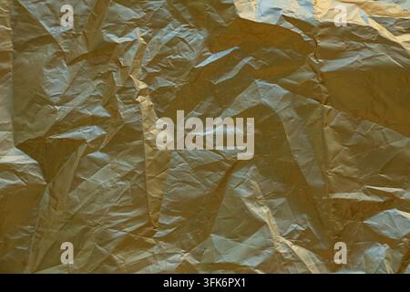 Crumpled gold foil texture background with metallic sheen and abstract wrinkles for design Stock Photo