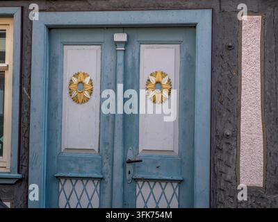 Charming vintage blue double door with golden sunflower medallions and lattice panels on a traditional German half-timbered building. Stock Photo