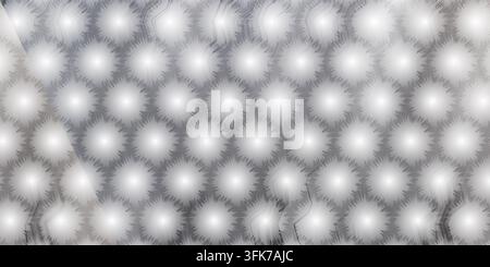 A sleek grey textured background featuring a repeating pattern of soft, glowing circular starbursts arranged in a geometric grid. Stock Photo