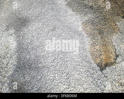 Rough granular asphalt surface displaying dark and light areas with varied texture Stock Photo