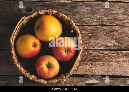 Top view ripe apples in wicker basket on an old rustic wooden background Stock Photo