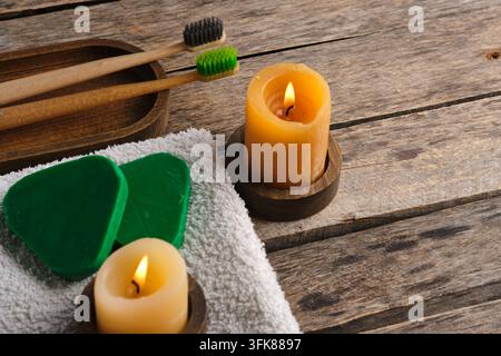 Eco friendly spa and bathroom flat lay featuring wooden toothbrushes, solid shampoo, candles, and towel Stock Photo
