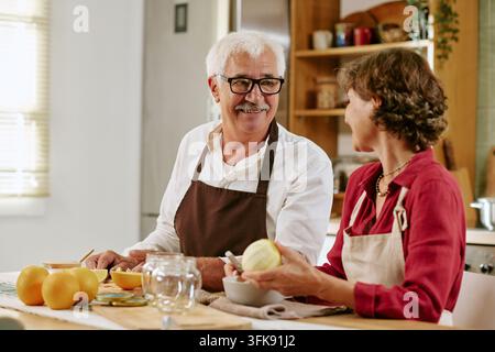 Senior Couple Preparing Healthy Citrus Fruit in Kitchen Stock Photo