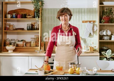 Portrait of Senior Woman Cooking Homemade Jam in Kitchen Stock Photo