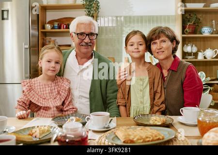 Portrait of Happy Grandparents Having Breakfast with Granddaughters at Home Stock Photo