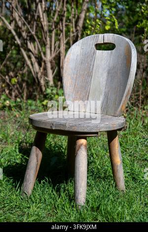 An old wooden chair with a crack is in the meadow, so you can take a seat to rest after a long walk. Stock Photo