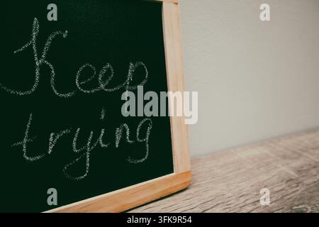 Keep trying text written on wooden frame school blackboard. Handwritten text on a blackboard Stock Photo