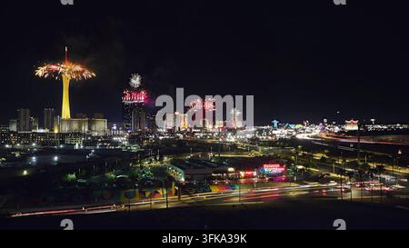 Vibrant aerial view of the Las Vegas Strip at night with fireworks lighting up the sky for the Fourth of July. The Stratosphere Tower neon city lights Stock Photo