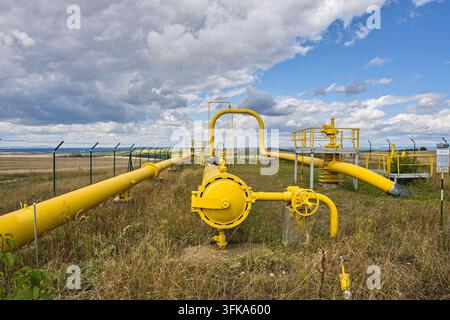 Yellow industrial gas pipeline distribution system running through an open landscape under a dramatic cloudy sky Stock Photo