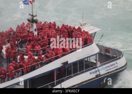 Passengers in red ponchos crowd the bow of a Niagara City Cruises boat on the Niagara River, Niagara Falls, Ontario, Canada. Stock Photo