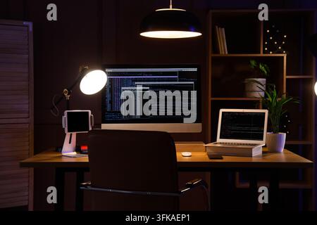 Software development and coding, programmer workspace with computer and laptop at night in home office with deadline pressure and remote work Stock Photo