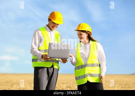 Construction project management and engineering, diverse team of architects using laptop on site for planning and infrastructure development in field Stock Photo